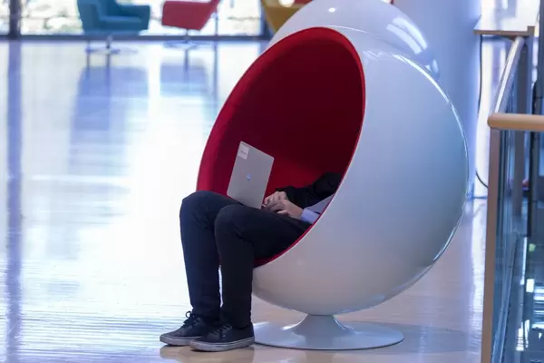 Mann bedient Laptop sitzend in einem Designer- Sessel