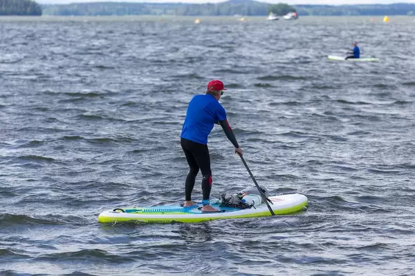 Mann benutzt beim Stand-up-Paddling die Fußschlaufe und paddelt über den Vesijärvi-See in Finnland