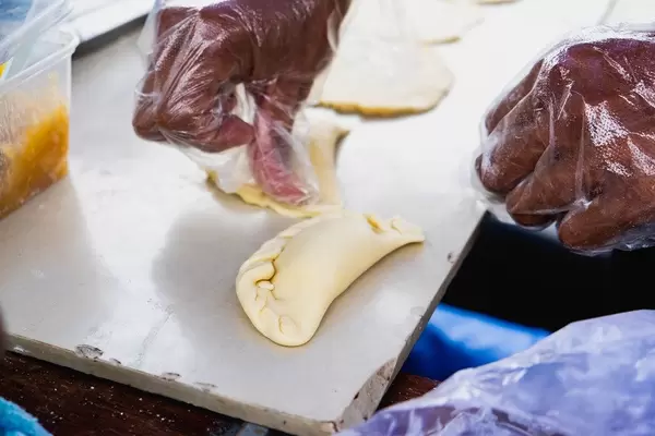 Mann bereitet den Teig von Empanada, einem traditionellen Latein-Amerikanischen Gebäck zum Backen vor