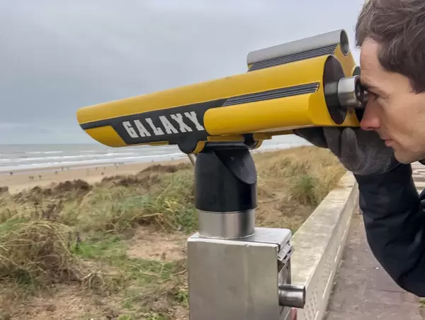 Mann blickt durch fest installiertes Fernrohr am Strand in Zandvoort, Niederlande