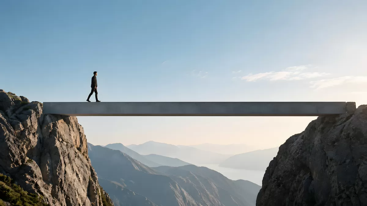 Mann geht über schmale Betonbrücke zwischen Berggipfeln