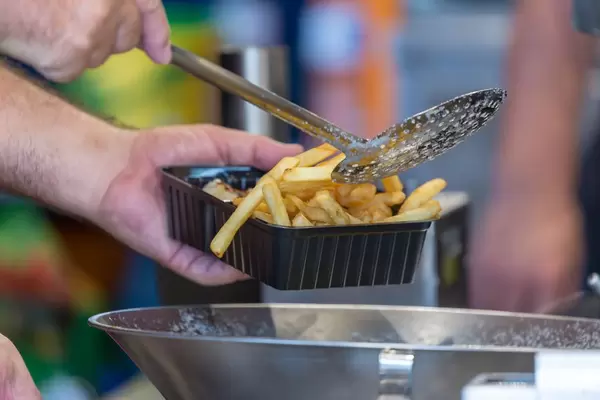 Mann gibt Pommes in eine Plastikschüssel ein