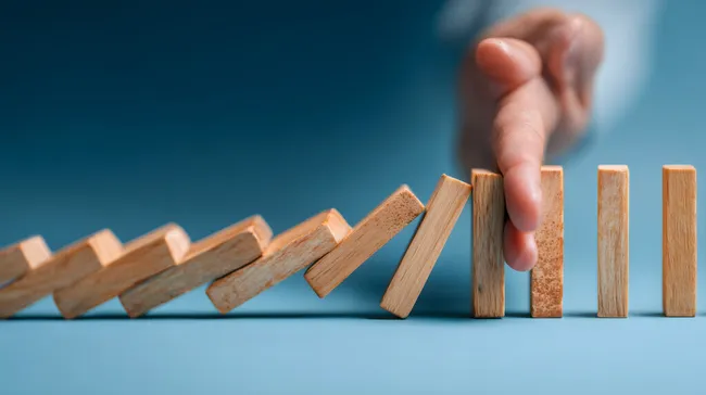 Mann hält Dominosteine an, bevor sie umkippen
