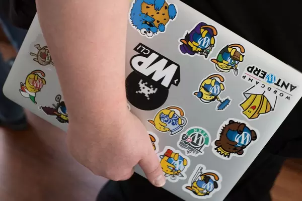 Mann hält ein Notebook in der Hand mit vielen Stickern auf dem Rückdeckel