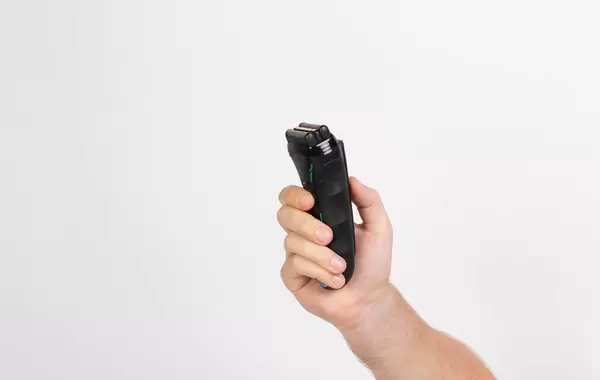 Mann hält einen elektrischen Rasierapparat in der Hand