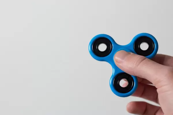 Mann hält Fidget Spinner zwischen seinen Fingern