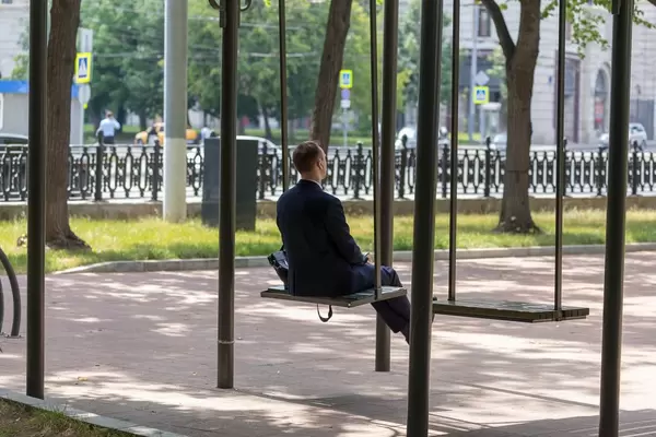 Mann im Anzug auf einer großen Schaukel im Park