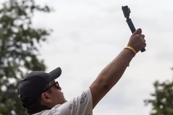 Mann in Baseballmütze hebt sein Hand und macht ein Video vom Tomorrowland Festival