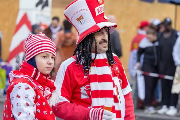 Mann in rot-weiß mit vielen Zöpfen trinkt Bier - Kölner Karneval 2018