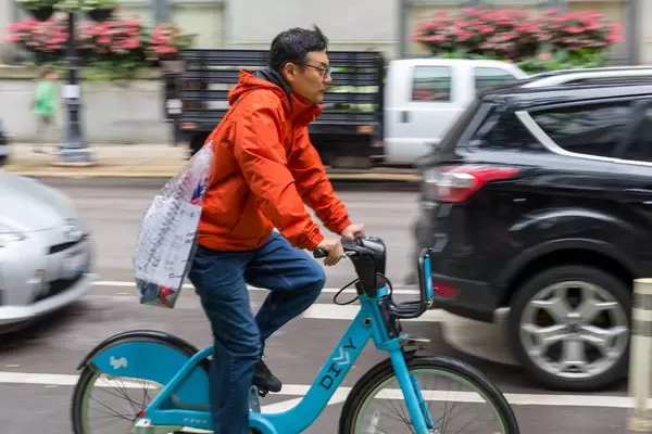Mann in roter Jacke erkundet Downtown Chicago mit einem blauen Leihfahrrad von Divvy
