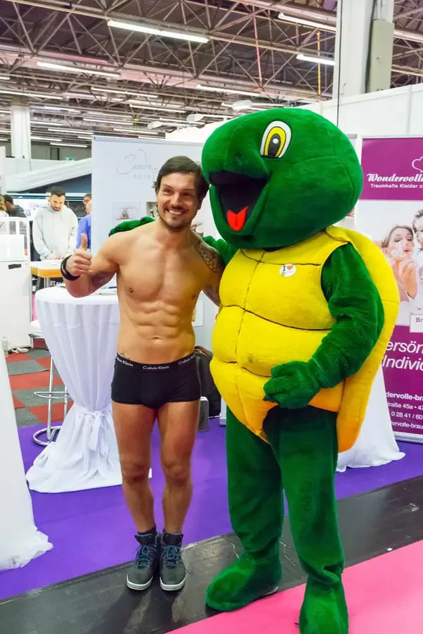 Mann in Unterhose lässt sich mit einem Maskottchen fotografieren