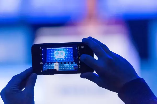 Mann macht ein Foto mit Smartphone bei der Rede von Tarana Burke auf dem Bits & Pretzels Festival in München