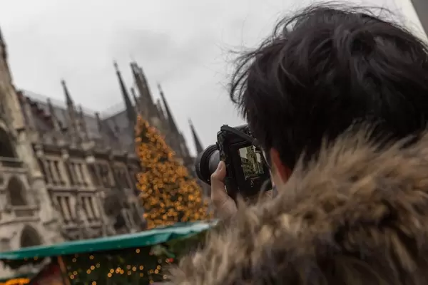 Mann macht Foto von Kölner Dom mit Weihnachtsbaum und Weihnachtsmarkt auf Domplatte