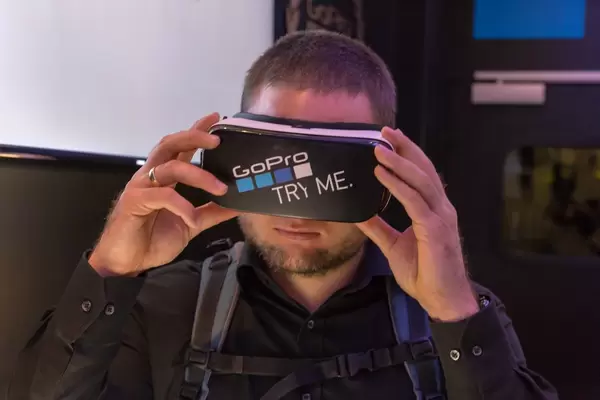 Mann mit aufgesetzter Samsung VR Brille mit GoPro Aufkleber an der Photokina in Köln