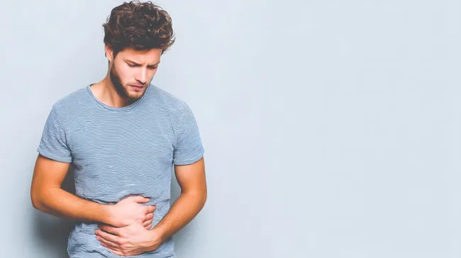Mann mit Bauchschmerzen in grauer Umgebung