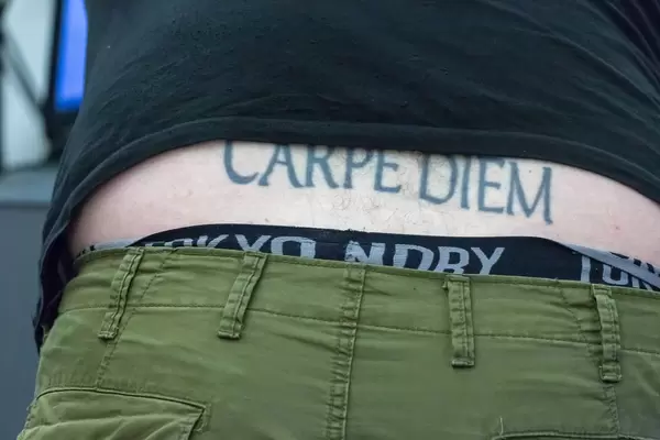 Mann mit Carpe Diem Steißbeintattoo