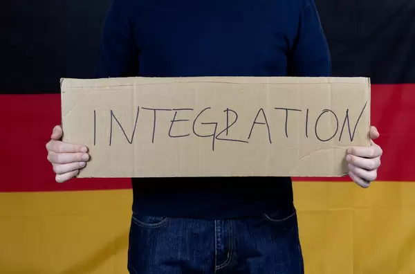 Mann mit Integration-Transparent vor deutscher Flagge