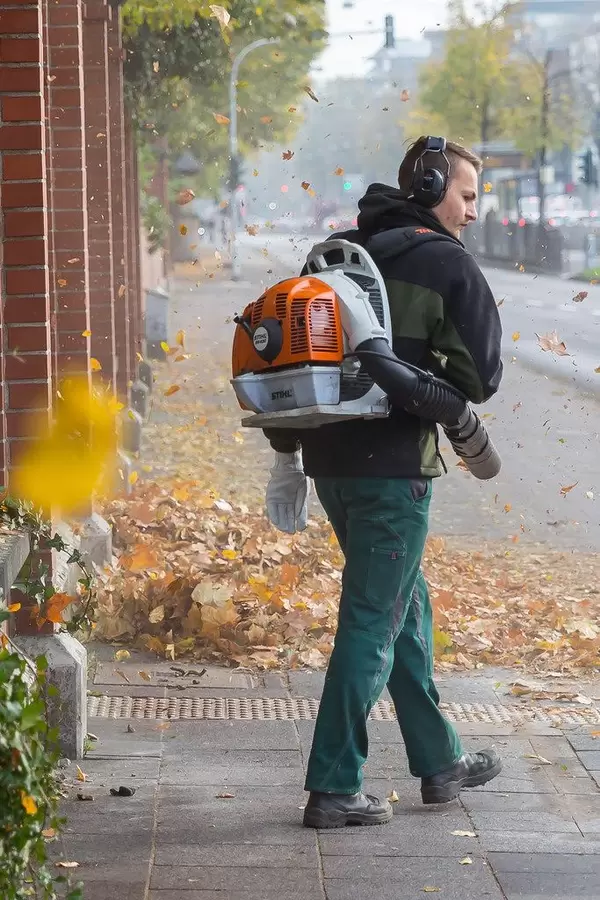 Mann mit Laubbläser und Ohrenschutz
