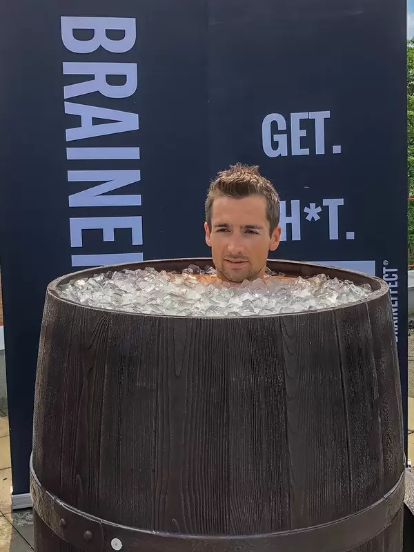 Mann nimmt ein Eisbad in einem alten Holzfass, um sich nach dem harten Training und Sport zu regenerieren
