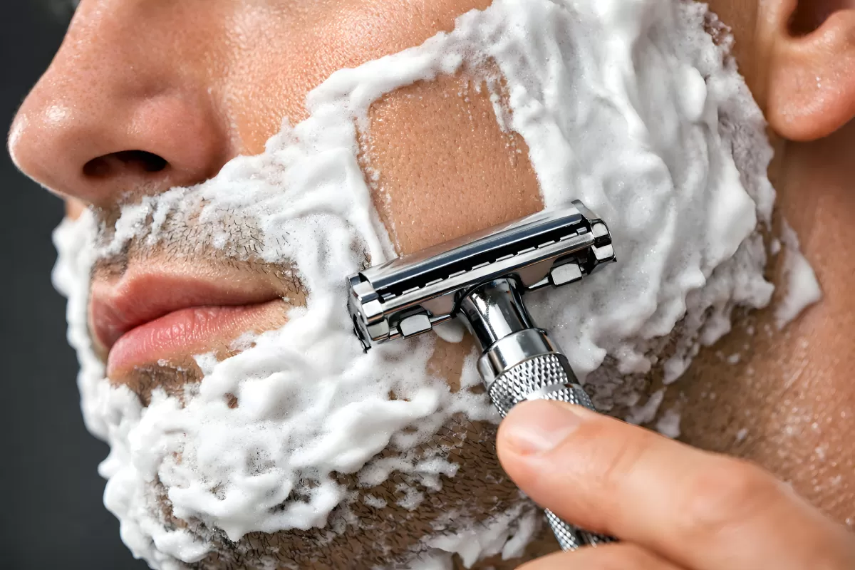 Mann rasiert sich Bart mit klassischem Rasierhobel