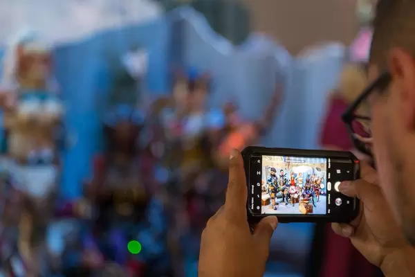 Mann schießt ein Foto mit dem Smartphone von der Cosplayszene am Messestand von Monster Hunter World: Iceborne