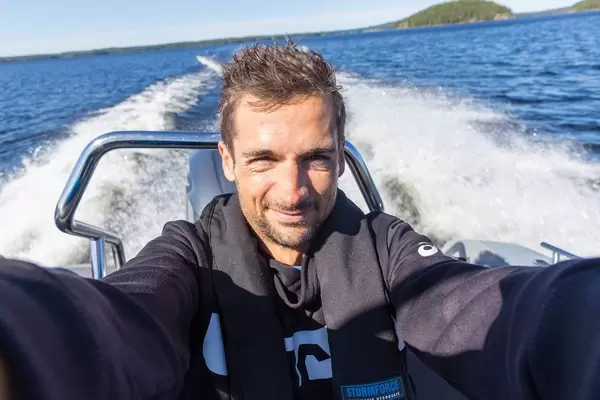 Mann schießt ein Selfie auf einem fahrenden Motorboot in blauem Gewässer des Päijännesees im Finnland-Urlaub