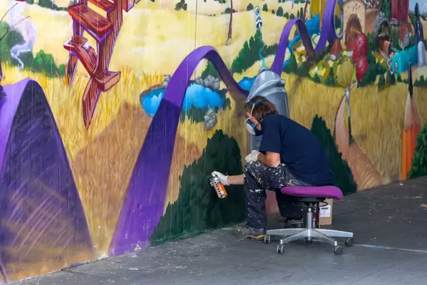 Mann sitzt auf einem Stuhl und sprüht Graffiti