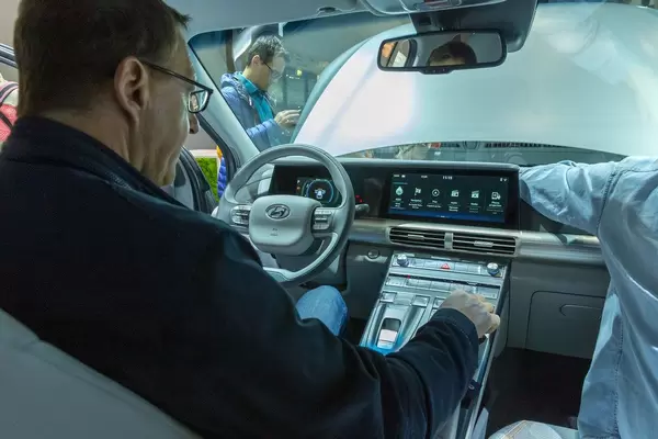 Mann sitzt im Innenraum vor den Bedienelementen des Hyundai Nexo Elektroauto mit Wasserstoff-Antrieb