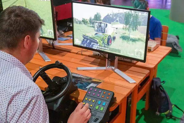 Mann spielt mit dem Cockpitnachbau von Logitech G Landwirtschafts-Simulator Bundle, mit Lenkrad-Controller und Seitenkonsole