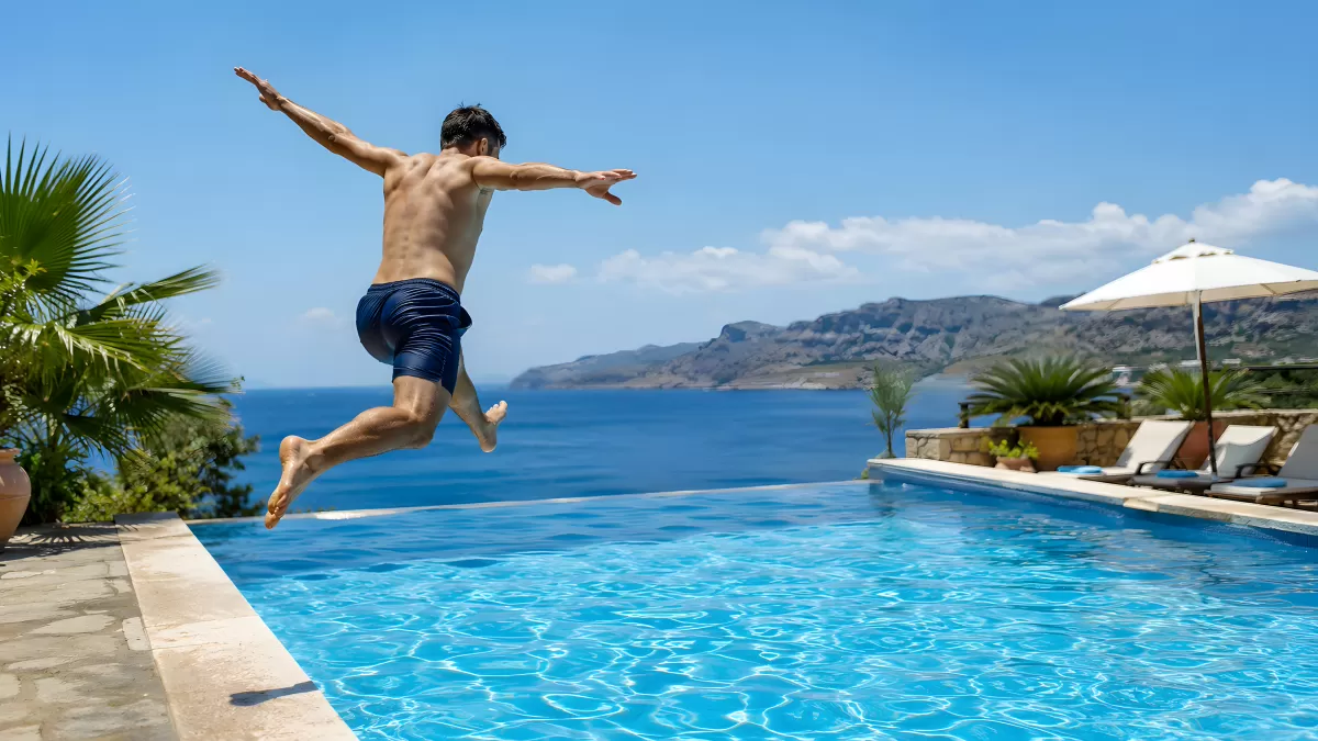 Mann springt in Infinity-Pool mit Meeresblick