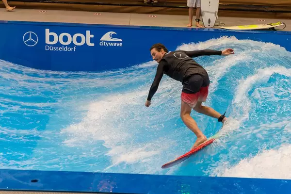 Mann surft und demonstriert stehende Welle mit kurzem Surfboard