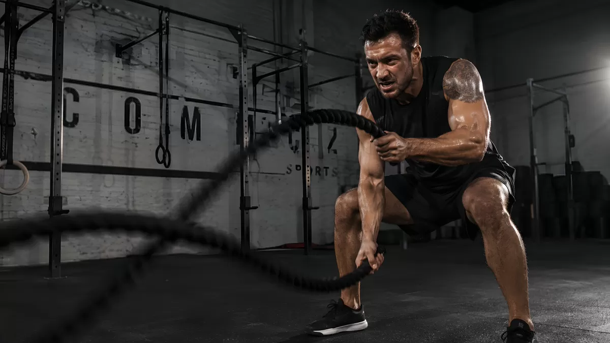Mann trainiert intensiv mit Battle Ropes im Gym