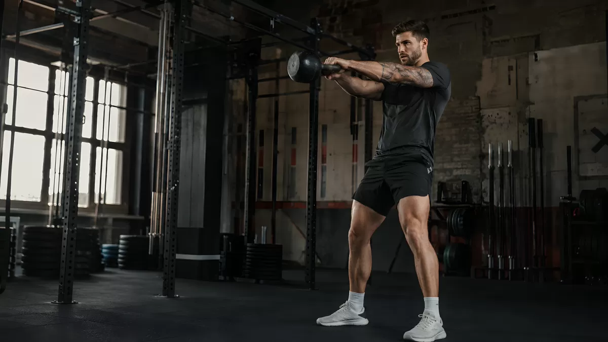 Mann trainiert mit Kettlebell in dunklem Fitnessstudio