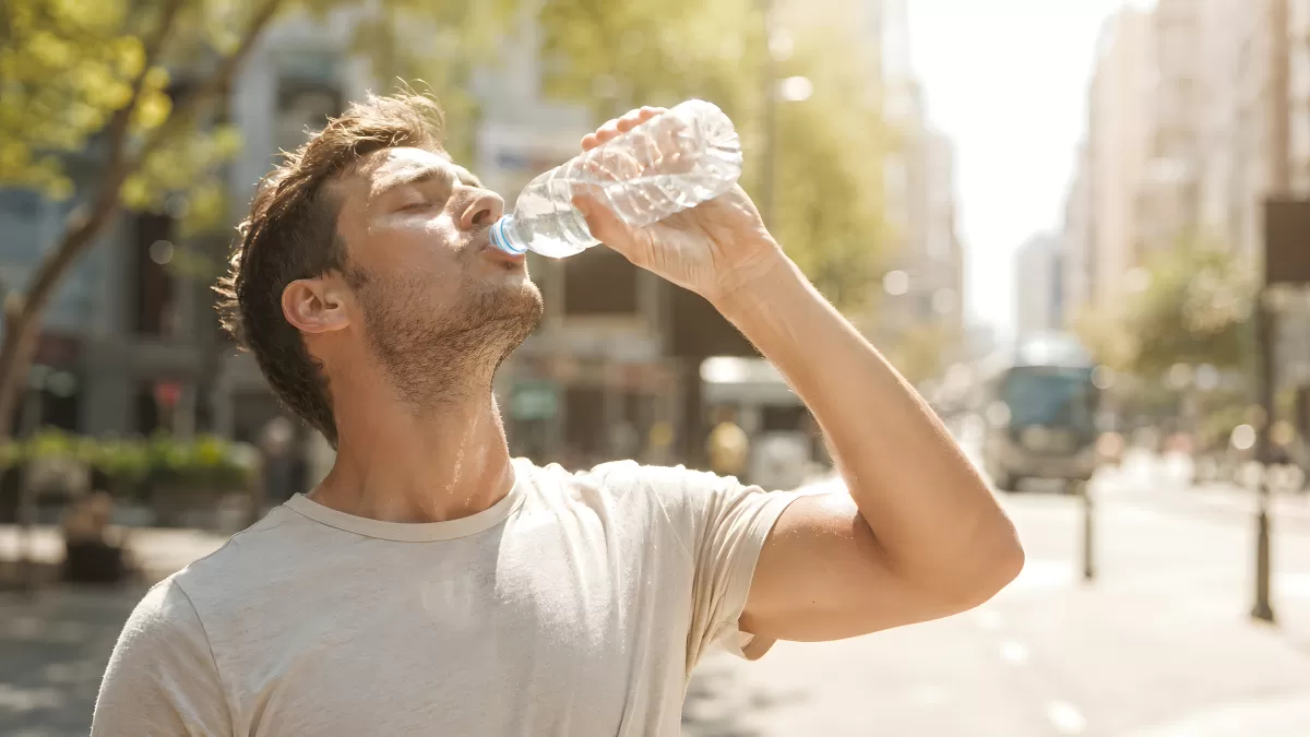 Mann trinkt Wasser aus Flasche bei Sommerhitze