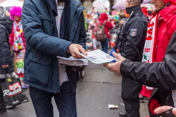 Mann verteilt Flyer für eine autofreies Stadt beim Rosenmontagszug in Köln