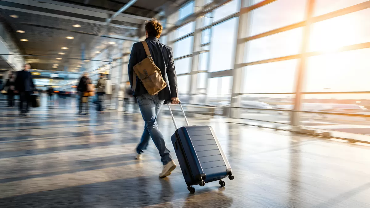 Mann zieht Trolley durch modernen Flughafenterminal