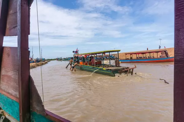 Männer helfen einem Boot dass auf einer Sandbank fest steckt in Siem Reap