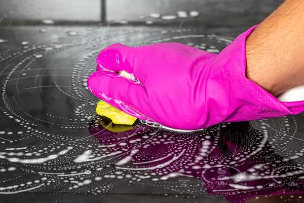 Man's hand with a rag wipes the kitchen cooking electrical surface