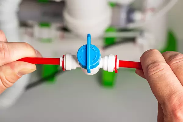 Man's hands hold hoses with a tap for a reverse osmosis filter