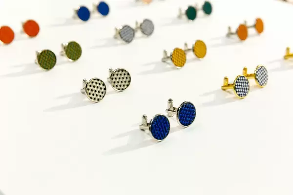 Manschettenknöpfe mit dreidimensionalem Karomuster in unterschiedlichen Farben auf weißem Tisch