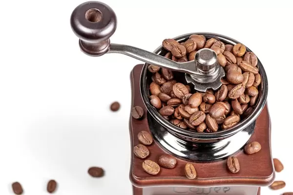 Manual coffee grinder with coffee beans on white background