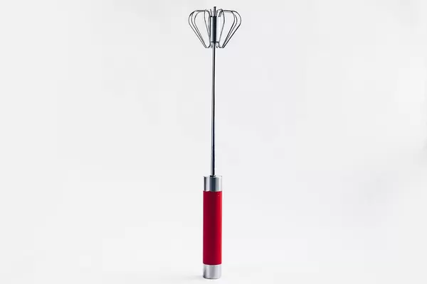 Manual whisk rotary egg beater on white background. Cooking tool.