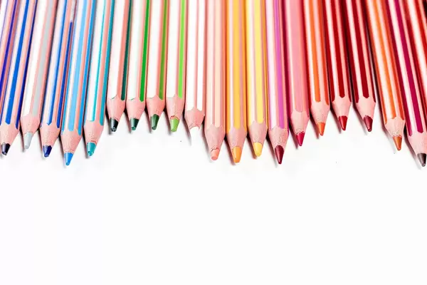 Many colored pencils on the white background with free space