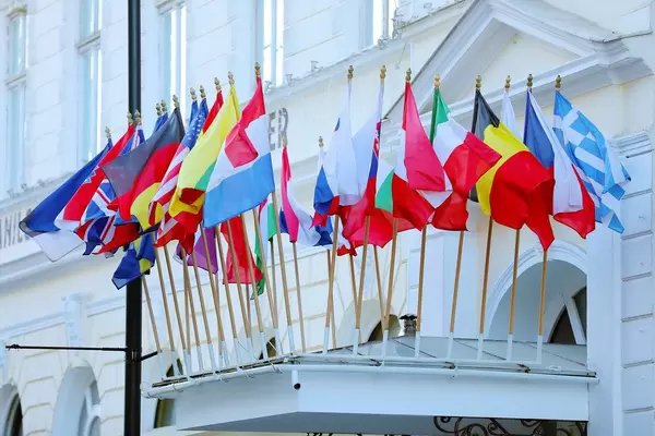Many flags on a building, including: Belgium, Greece, USA, UK, Italy, France, Russia, Austria, Germany