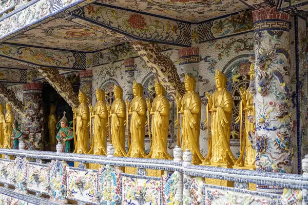 Many Golden Lady Buddha Statues in front of a Mosaic Wall at Linh Phuoc Pagoda in Da Lat, Vietnam