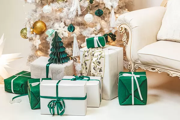 Many white and green presents on the floor under the tree