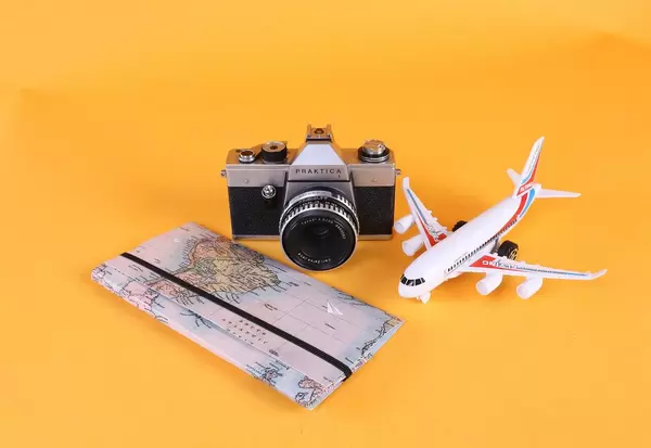 Map, vintage camera and airplane on orange background