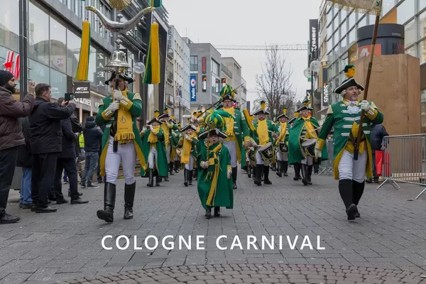 Marching band with children, men and woman in guard costumes during rose Monday at Kölner Karneval, walking through the streets, with the picture title "Cologne Carnival"
