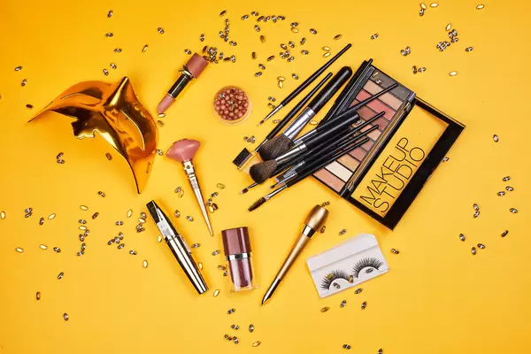Mardi Gras mask and carnival make-up tools on yellow