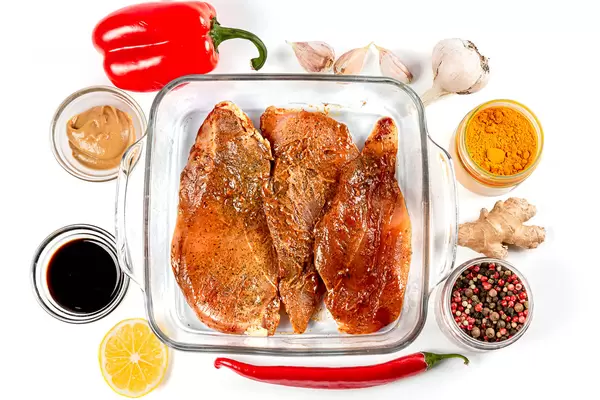 Marinated chicken fillet with spices in a glass baking sheet, top view